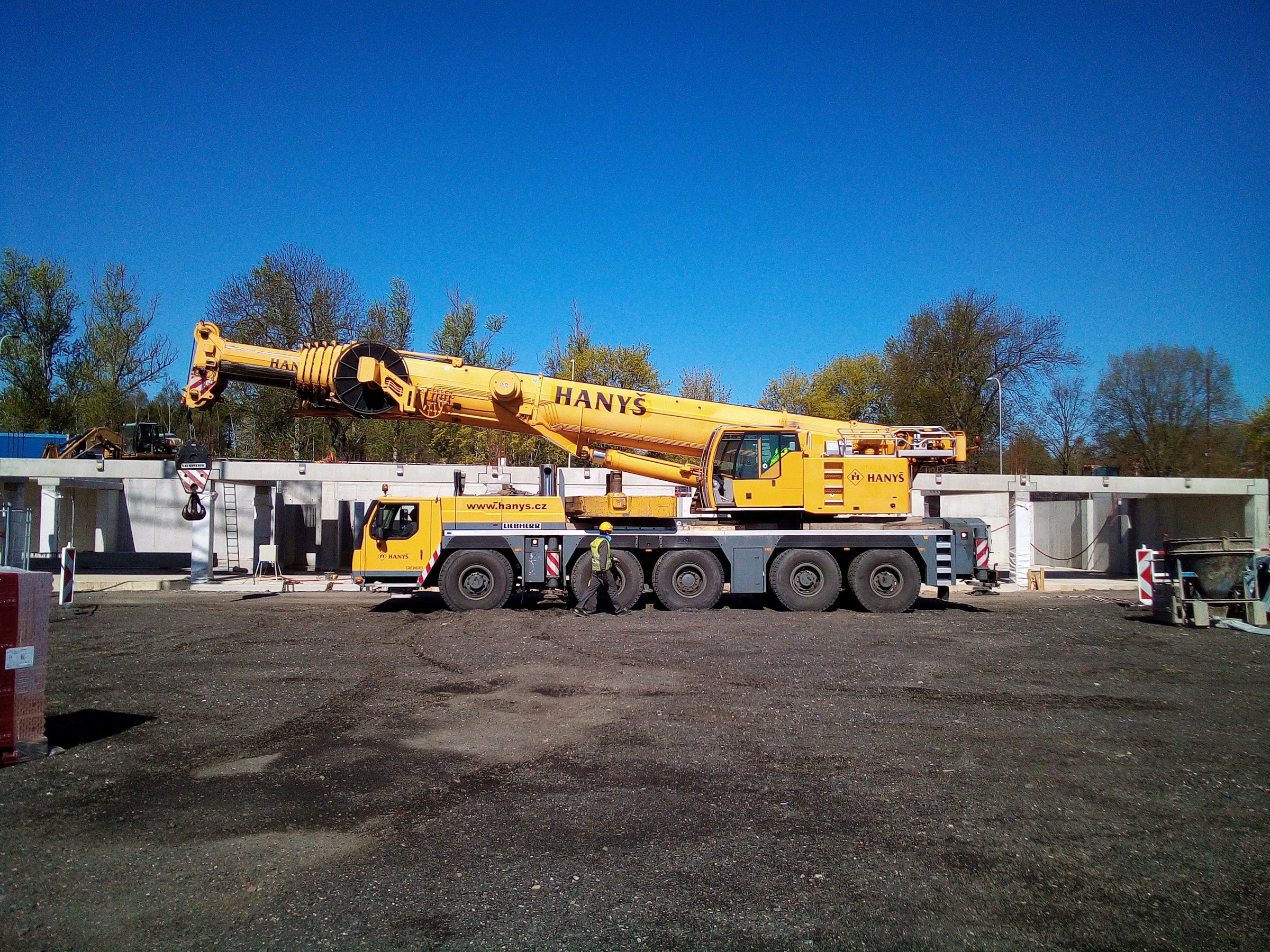 All-terrain mobile crane with boom stowed, parked on a gravel yard