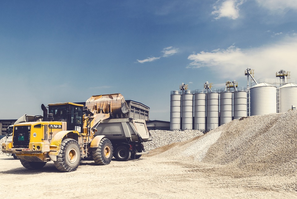 Wheel loader working an aggregate stockpile beside cement silos