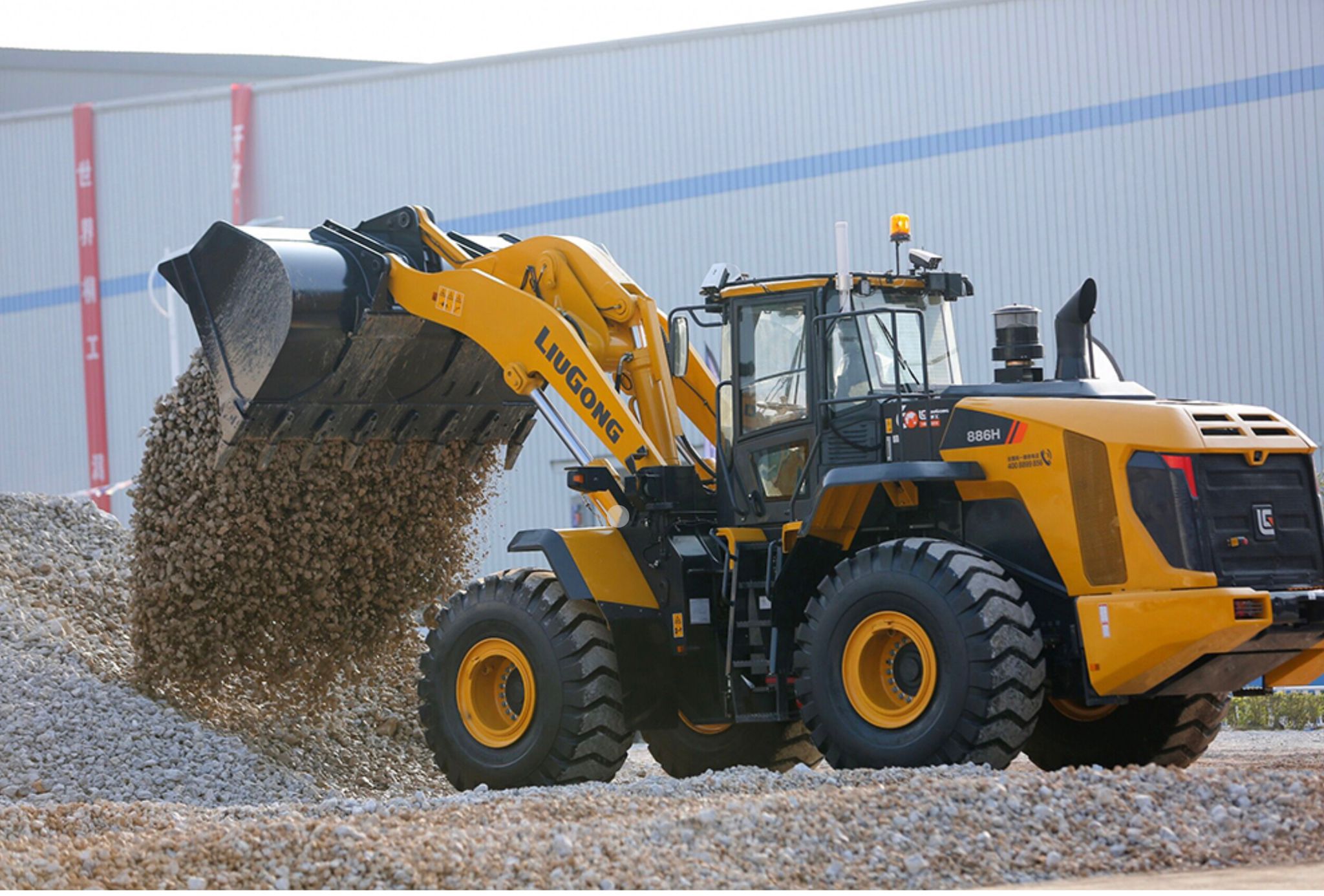 Wheel loader tipping a full bucket of aggregate onto a stockpile